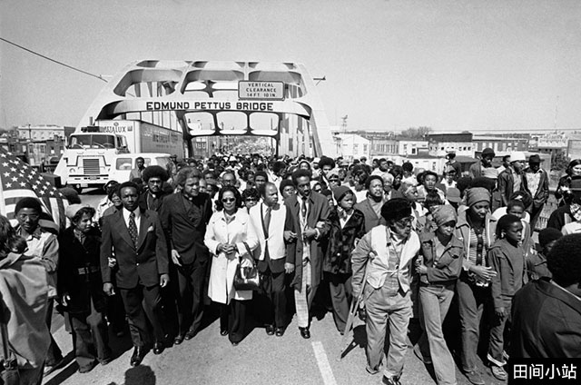 1975年,马丁·路德·金的遗孀科雷塔•斯科特•金(Coretta Scott King,中)和约翰·刘易斯(John Lewis)(现任国会众议员)走过埃德蒙·佩特斯大桥(Edmund Pettus Bridge),纪念发生在1965年3月7日的“血腥星期日”(Bloody Sunday)事件。在那次事件中,刘易斯和其他和平示威者遭到警察殴打。 1975年,马丁·路德·金的遗孀科雷塔•斯科特•金(Coretta Scott King,中)和约翰·刘易斯(John Lewis)(现任国会众议员)走过埃德蒙·佩特斯大桥(Edmund Pettus Bridge),纪念发生在1965年3月7日的“血腥星期日”(Bloody Sunday)事件。在那次事件中,刘易斯和其他和平示威者遭到警察殴打。